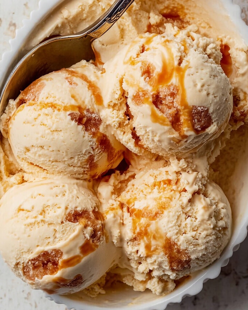 The image shows five scoops of creamy beige ice cream with visible swirls of golden caramel throughout. The ice cream texture looks smooth and soft with some icy crystal spots, and the caramel swirl adds a sticky, shiny contrast. The scoops sit closely together in a white bowl that has a subtle scalloped edge, and a silver spoon holds one scoop near the top left. The background features a white marbled texture. photo taken with an iphone --ar 4:5 --v 7