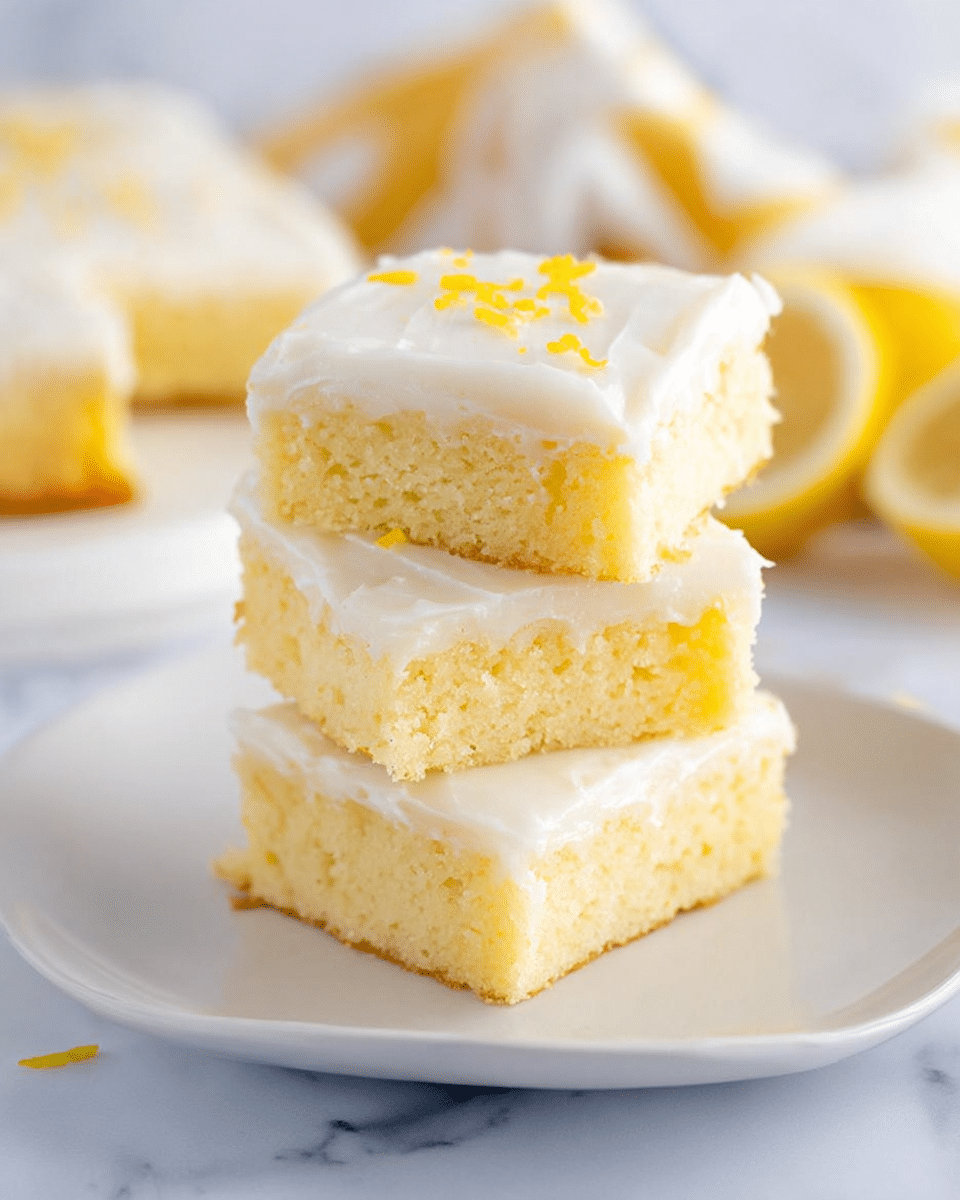 A close-up image of a three-layer yellow cake square on a white plate, each layer separated by a thin smooth white frosting layer. The cake layers are soft and moist with a light crumb texture, while the top layer is covered with a smooth white frosting sprinkled lightly with small yellow zest bits. One corner of the cake has a bite taken out, showing the moist texture inside. The plate rests on a white marbled surface with soft blurred yellow and white fabric in the background. photo taken with an iphone --ar 4:5 --v 7