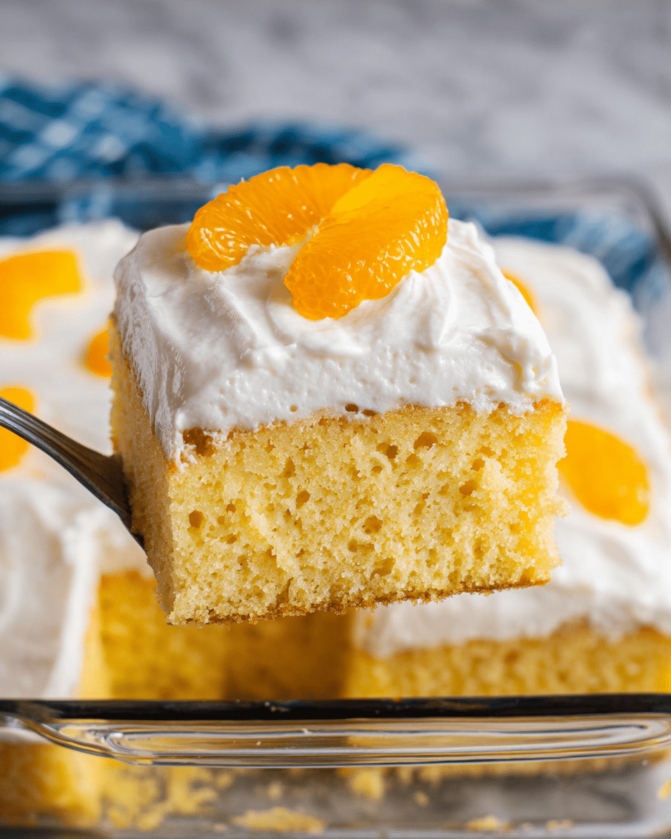 A close-up of a square slice of yellow sponge cake with a thick, creamy white frosting layer on top, showing a soft and moist texture with small air holes in the cake. The frosting looks smooth but slightly textured, covering the entire top surface. A bright orange mandarin slice sits on the frosting for decoration. The slice is being lifted by a metal utensil above a clear glass baking dish filled with more of the same cake and frosting, all set on a white marbled surface. Photo taken with an iphone --ar 4:5 --v 7