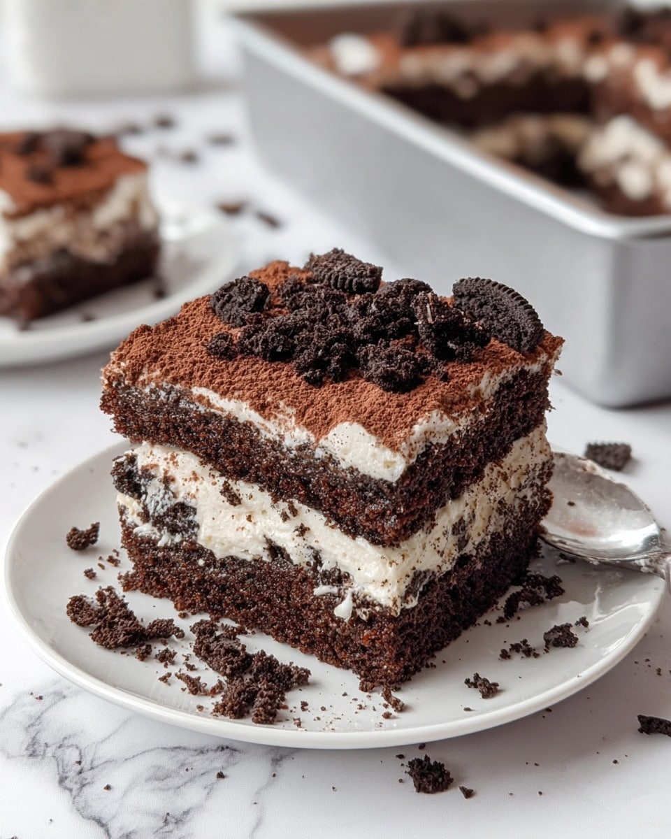 A square-shaped chocolate dessert is shown in a well-used silver baking pan with some dark spots on the edges. The dessert has three main layers: the bottom and middle layers are dark, moist chocolate cake, and the middle layer holds a creamy white filling. The top layer is covered with a thick dusting of cocoa powder and sprinkled with crushed dark chocolate cookie pieces, creating a rough texture. The dessert is cut into nine even squares, with one piece missing from the front corner, revealing the creamy and chocolate layers inside. The whole scene is set on a white marbled surface. photo taken with an iphone --ar 4:5 --v 7