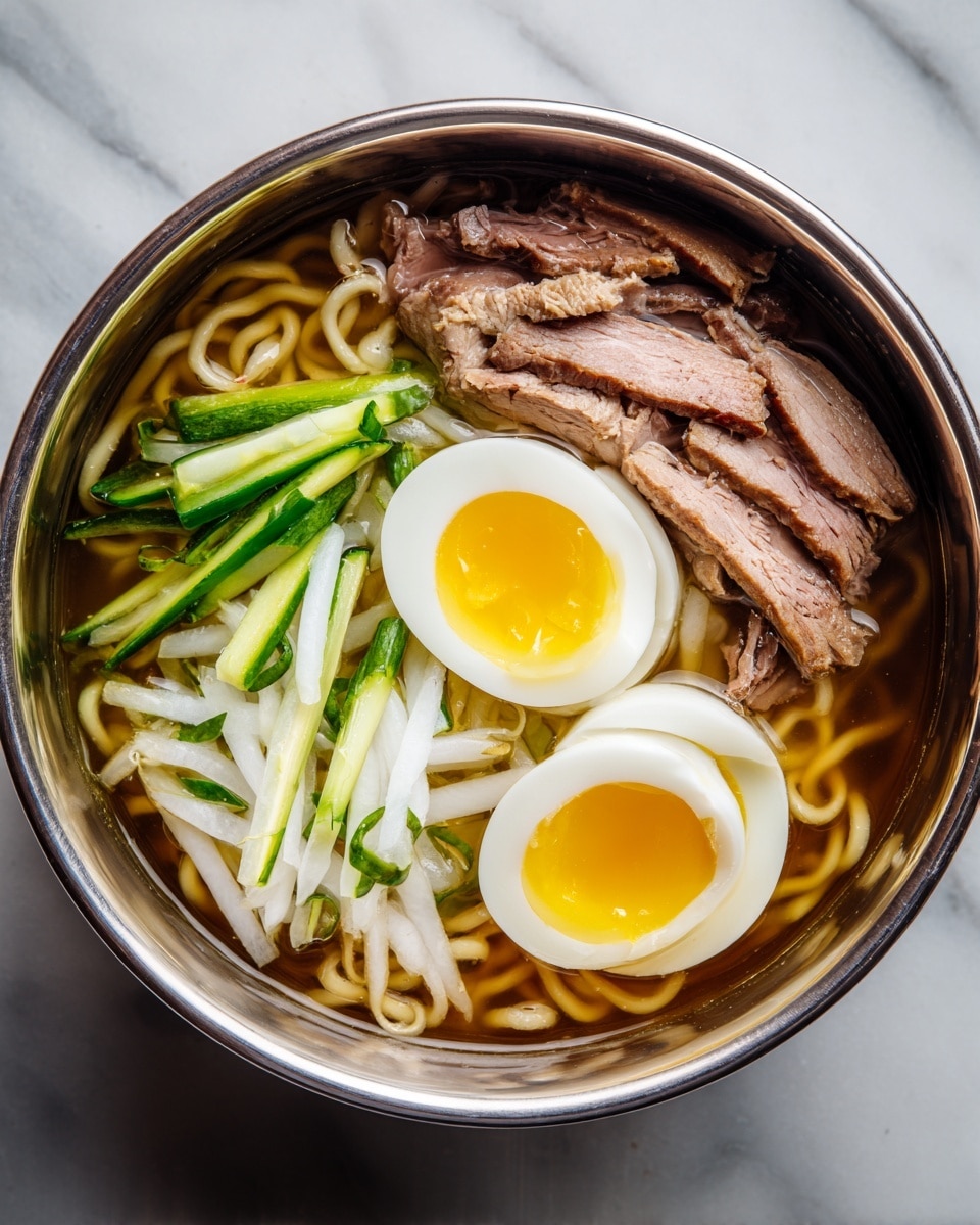 A close-up of a bowl of cold noodle soup with clear, light golden broth filling the white bowl. In the center, there is a neat pile of thin brown noodles. On top of the noodles, there are thin strips of light green cucumber and bright green scallions arranged loosely. Sitting on top of these vegetables is a half of a boiled egg with a bright yellow yolk and white edges. The bowl is placed on a white marbled surface, with another similar bowl blurred in the background. photo taken with an iphone --ar 4:5 --v 7
