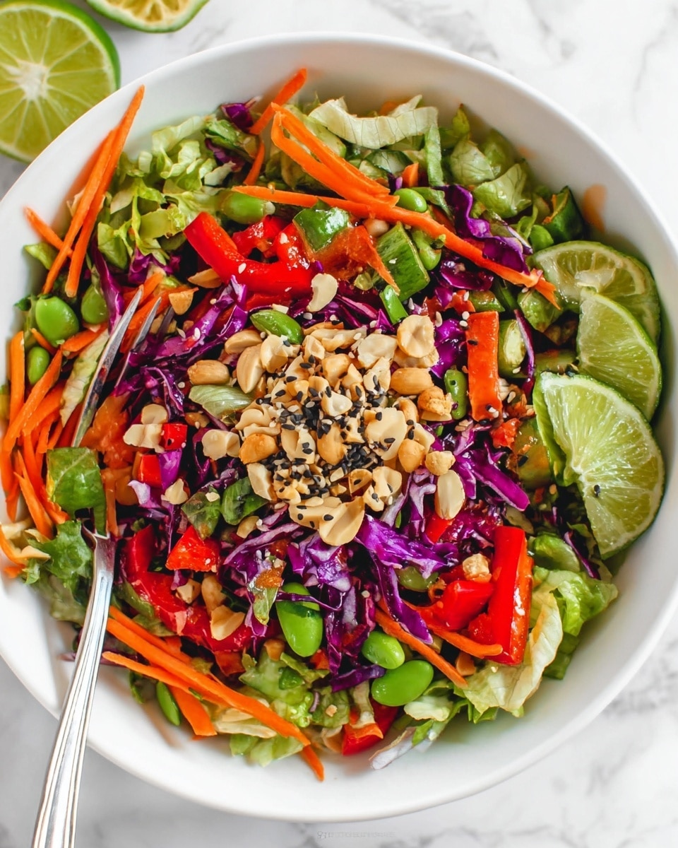 A white bowl filled with a colorful mixed salad resting on a white marbled surface, featuring a base layer of chopped green lettuce and purple cabbage, topped with thin orange carrot strips, chunks of red bell pepper, and bright green snap peas. In the center, there is a small mound of mixed nuts including peanuts and sliced almonds, sprinkled with black sesame seeds, and garnished with fresh lime wedges on the side. A fork is placed in the salad as if ready to serve. photo taken with an iphone --ar 4:5 --v 7