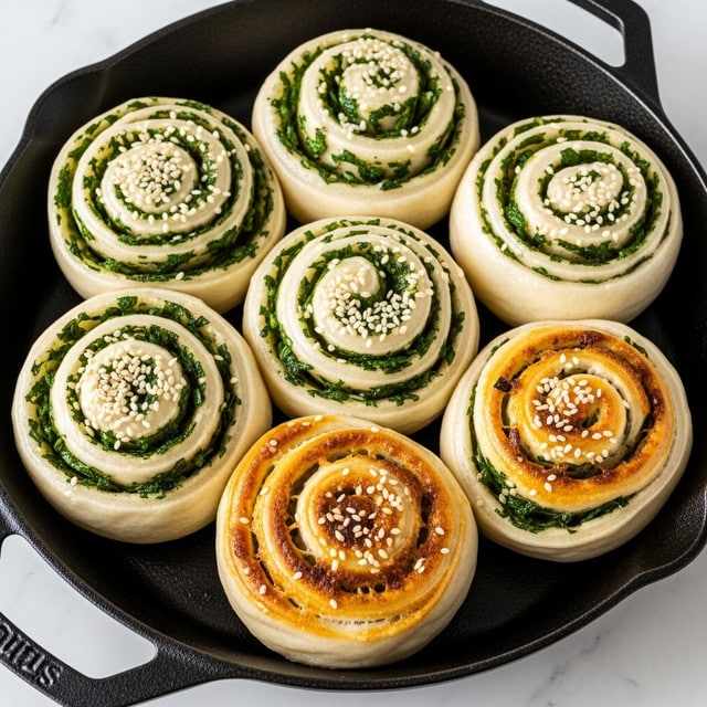 The image shows seven round, twisted buns cooked in a black cast iron pan. Each bun has multiple layers with a light dough color, mixed with green bits of chopped herbs inside and on top, and sprinkled with white sesame seeds. Some buns have a golden brown crispy top that contrasts with the lighter parts of the dough, showing they are fried or baked. The buns are arranged close to each other inside the pan, which sits on a white marbled surface. Photo taken with an iphone --ar 4:5 --v 7