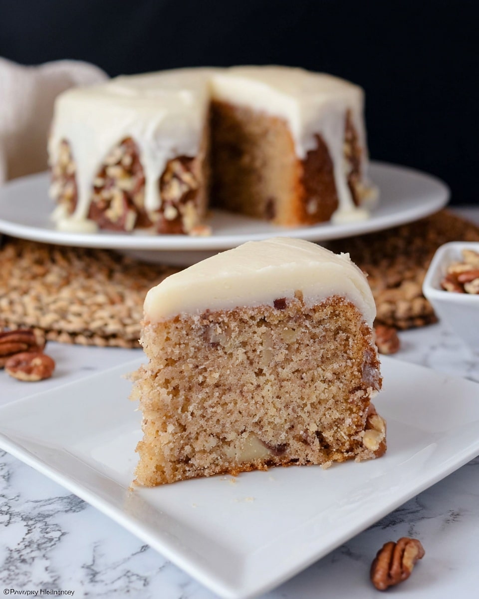 A single tall slice of nut-filled cake with a moist, light brown texture sits on a white square plate. The slice has small pieces of nuts embedded throughout its crumb. On top is a thick, smooth layer of white frosting that slightly drips down the edges. In the background, the rest of the round cake with the same frosting is visible on a white plate, placed on a natural woven mat. There are some scattered whole nuts around the base of the cake. The scene is set against a dark backdrop with a white marbled surface beneath. photo taken with an iphone --ar 4:5 --v 7