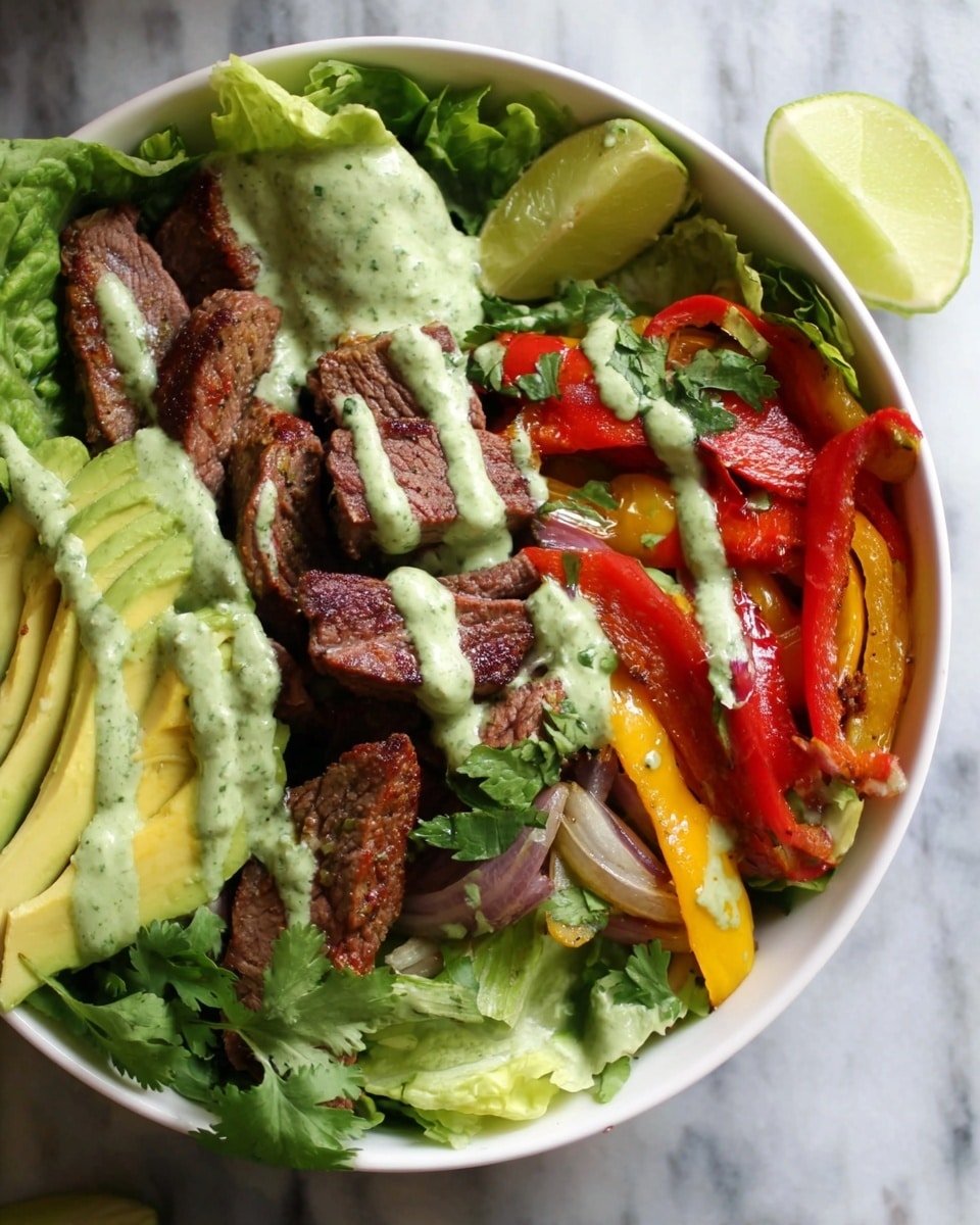 A white bowl filled with a fresh, colorful salad layered with leafy green lettuce at the base. On one side, thick slices of ripe avocado are placed neatly, topped with a creamy green sauce that is drizzled over the whole dish. In the center, there are several pieces of grilled steak showing a browned, slightly charred texture. To the right, strips of red and yellow bell peppers and sautéed onions add bright red, yellow, and purple colors. Wedges of fresh lime and sprigs of cilantro are scattered over the salad, adding fresh green accents. The dish sits on a white marbled surface. Photo taken with an iphone --ar 4:5 --v 7