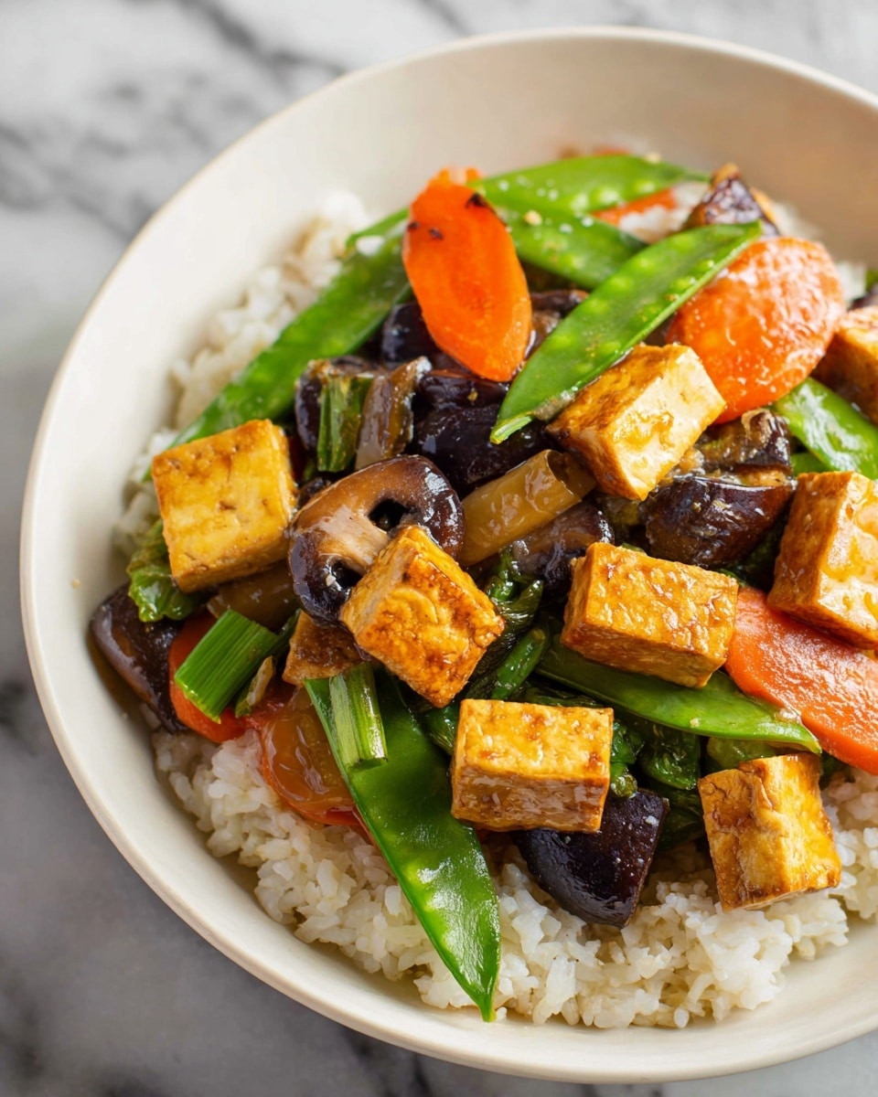 A white bowl holds a colorful dish with three main layers. At the bottom is a layer of white cooked rice with soft, separate grains. On top of the rice, there is a vibrant mix of vegetables including bright orange carrot slices, shiny green snap peas, dark brown mushrooms, and light green celery pieces. Scattered above the vegetables are small cubes of golden-brown tofu with a slightly crispy texture, some showing a light glaze of sauce adding a glossy finish. The whole dish is placed on a white marbled surface. photo taken with an iphone --ar 4:5 --v 7
