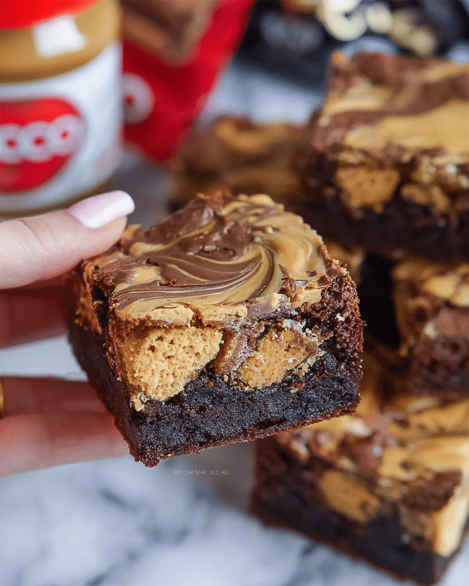 A close-up of a woman's hand holding a thick square brownie with three visible layers: the bottom layer is dark chocolate with a dense, slightly crumbly texture mixed with pieces of chocolate bars, the middle layer has chunks of golden brown biscuit showing a crunchy texture, and the top layer is swirled with smooth, light brown creamy peanut butter creating a marbled effect. In the background, more brownies with the same layered pattern are stacked, all placed on a surface with a white marbled texture, alongside a jar of smooth peanut butter with a red lid. Photo taken with an iphone --ar 4:5 --v 7
