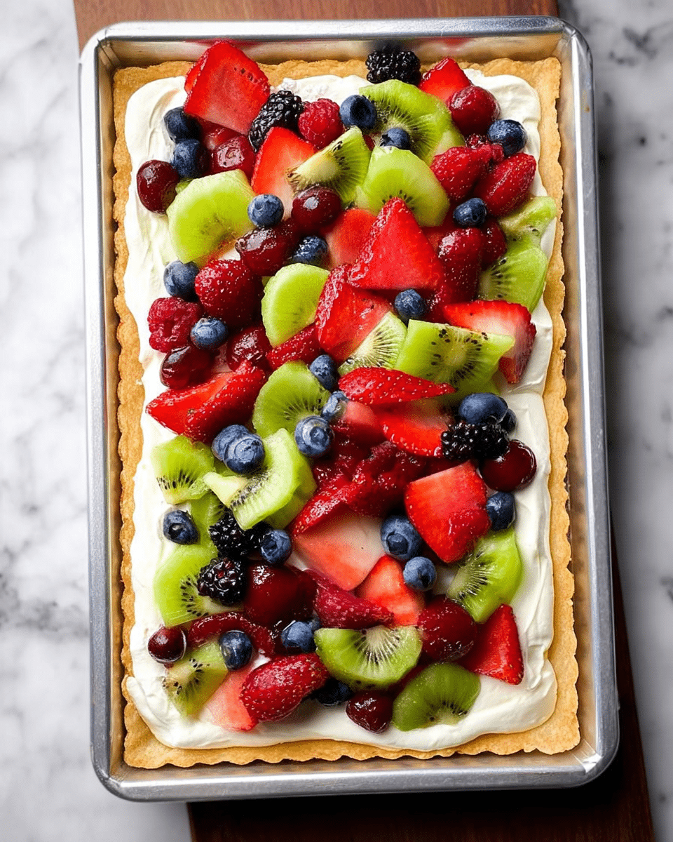 A rectangular tart with a golden crust forms the bottom layer, topped by a smooth, thick white cream layer spread evenly. On top, a colorful mix of fresh fruits is scattered: bright red strawberry slices, green kiwi chunks, deep blue blueberries, red raspberries, shiny red grape halves, and a few blackberries, creating a vibrant, textured surface. The tart is placed in a silver baking pan, all set on a white marbled surface. photo taken with an iphone --ar 4:5 --v 7