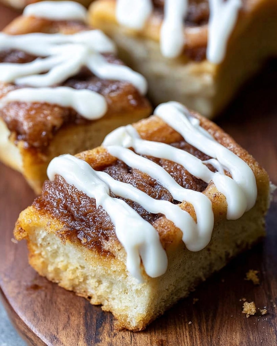 The image shows three pieces of cinnamon roll with icing on top. Each piece has two layers: the bottom layer is a thick, soft, light golden-brown bread, and the top layer is a darker cinnamon sugar coating with a slightly crispy texture. A thick line of white creamy icing zigzags across the cinnamon layer of each piece. The rolls are placed closely together on a wooden surface with some crumbs visible around them. Photo taken with an iphone --ar 4:5 --v 7