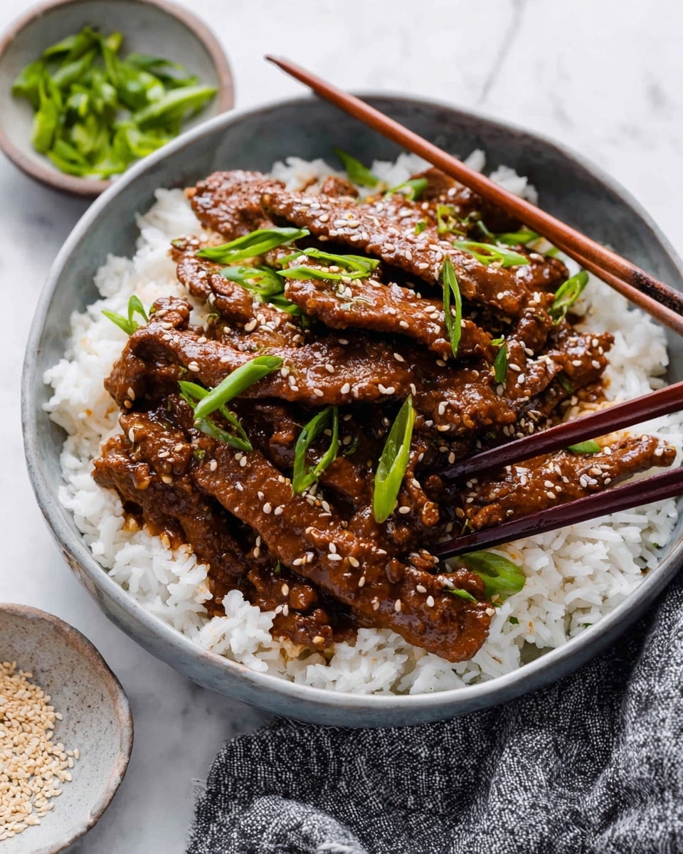 A white bowl filled with two layers shows a base layer of soft, fluffy white rice, with long grains visible. On top sits a thick layer of thin, brown beef strips coated in a shiny sauce with sesame seeds sprinkled all over, adding texture. Bright green chopped scallions are scattered on the beef, adding fresh color. Dark brown wooden chopsticks pick up some beef from the bowl. The bowl is on a white marbled surface, next to small bowls of chopped scallions and sesame seeds, with a textured grey cloth nearby. photo taken with an iphone --ar 4:5 --v 7
