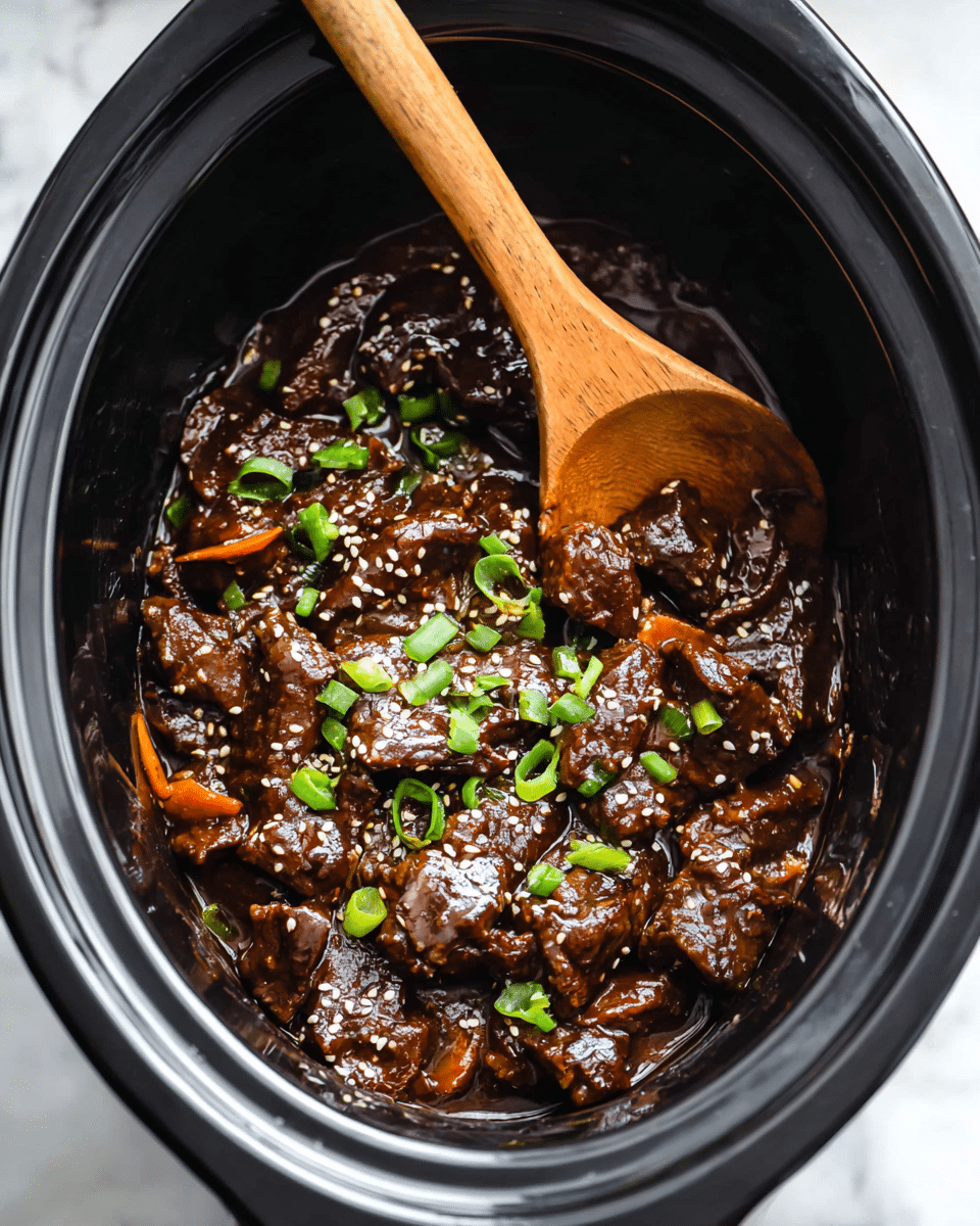 This image shows a close-up of a slow cooker filled with dark brown, glossy beef pieces coated in a thick sauce. The beef is layered evenly inside the cooker, with visible small orange carrot strips mixed throughout. The dish is garnished with bright green chopped scallions and sprinkled with white sesame seeds on top, adding texture and color contrast. A wooden spoon with a light brown handle rests in the cooker, partially submerged in the sauce. The setting is on a white marbled surface. photo taken with an iphone --ar 4:5 --v 7