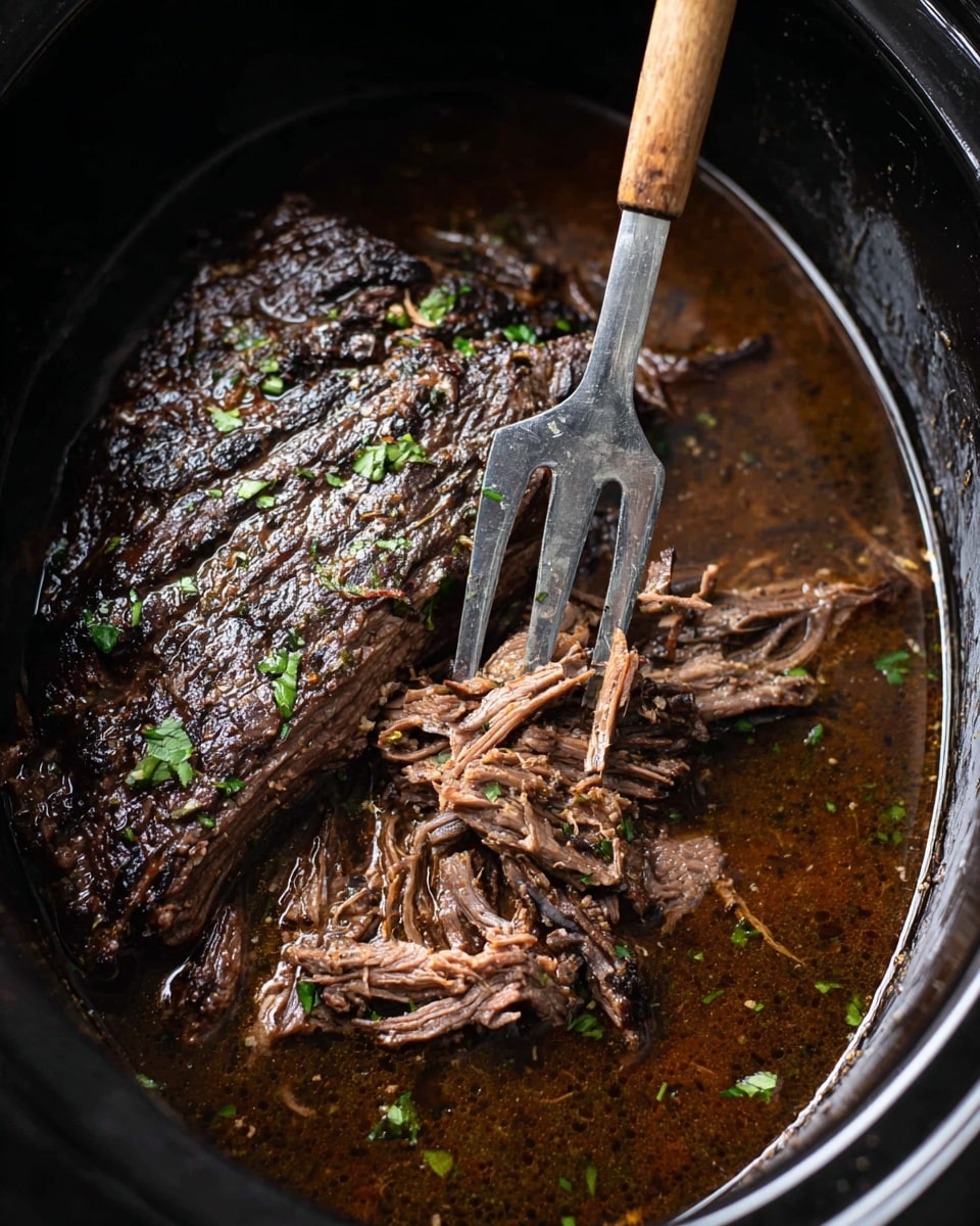 A slow-cooked piece of beef with a dark brown, slightly charred outer layer sits inside a black pot filled with rich brown juices. The top of the meat is sprinkled with small bits of green herbs, adding a fresh contrast to the dark, tender meat. Part of the meat is shredded, revealing a moist, fibrous texture that shows its softness. A two-pronged silver fork with a wooden handle presses into the meat, slightly lifting the shredded piece. The pot surrounds the meat with its smooth black surface, and some herb pieces float in the liquid around it. photo taken with an iphone --ar 4:5 --v 7