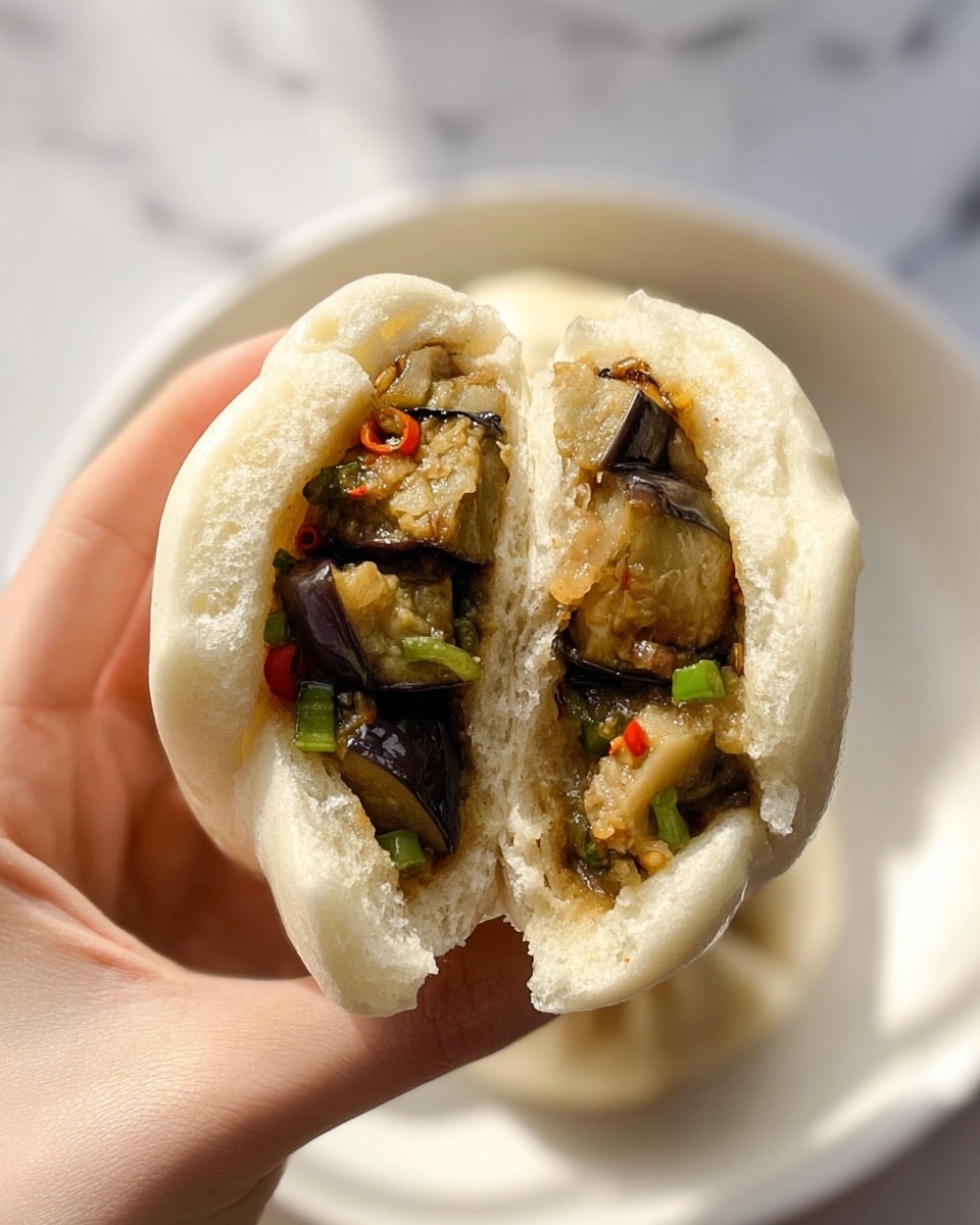 A close-up image of a white steamed bun held by a woman's hand, split open to show its inside layers. The bun outer layer is soft and fluffy with a pale cream color and a smooth texture. Inside, there are several chunks of cooked eggplant with a glossy, slightly brownish-purple look, mixed with green chopped scallions and small pieces of red chili adding a pop of color. The filling looks moist and tender, tightly packed within the thick bun. The background is a white marbled texture with a white plate partially visible behind the bun, blending softly into the setting. Photo taken with an iphone --ar 4:5 --v 7