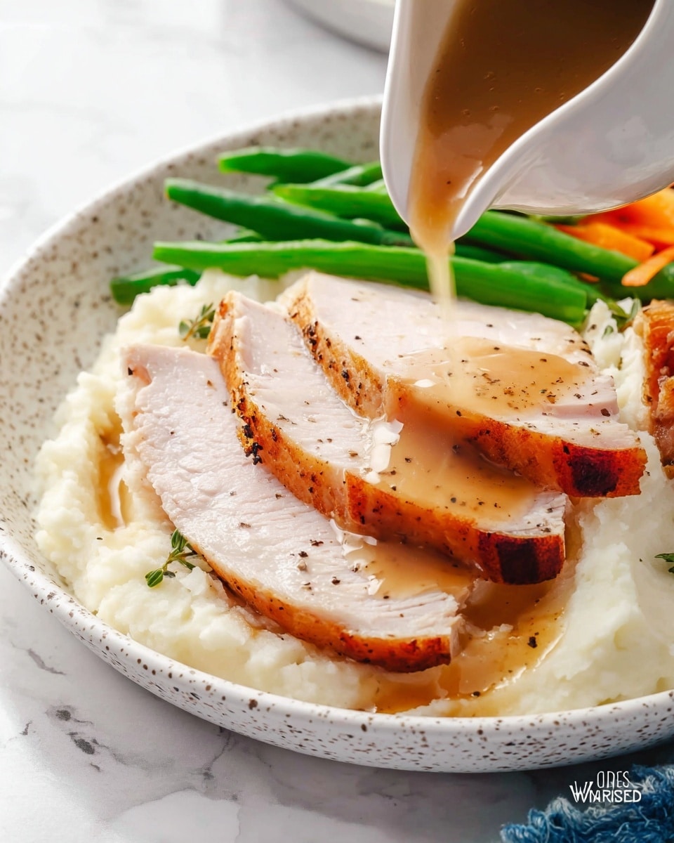 A white speckled plate holds a layered meal with three thick slices of light pink roasted turkey breast with golden brown edges placed on top of creamy mashed cauliflower, which is white with small green herb bits and black pepper on its smooth surface. At the back, vibrant green steamed vegetables peek out just above the turkey. A light brown gravy is being poured from a white gravy boat onto the top turkey slice, creating a glossy, flowing texture over the meat and pooling slightly on the plate's surface. The plate rests on a white marbled surface. photo taken with an iphone --ar 4:5 --v 7