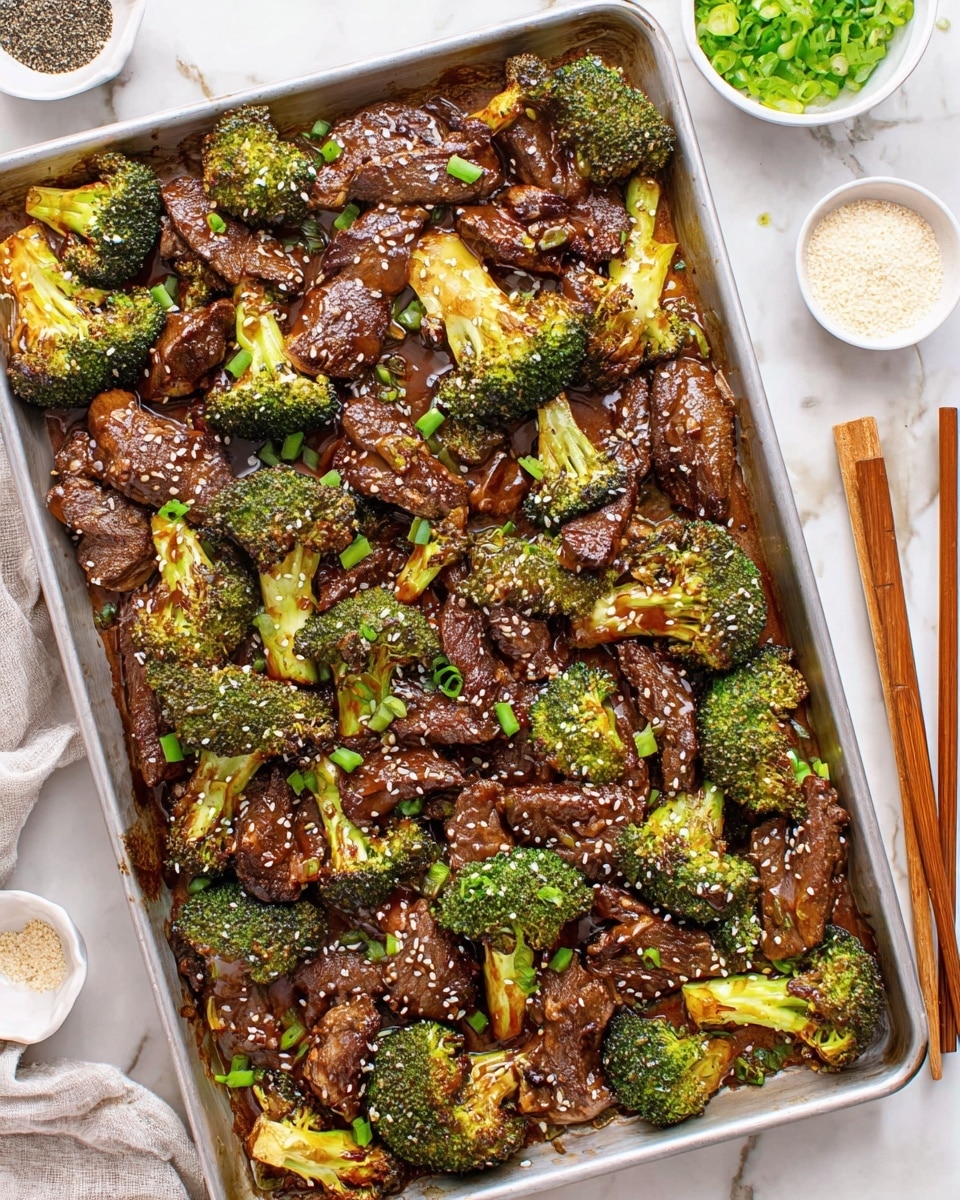 The image shows a large silver baking tray filled with cooked beef strips and roasted broccoli florets. The beef is dark brown with a glossy texture from a thick sauce covering most pieces, while the broccoli is bright green with browned edges from roasting. The dish is sprinkled with white sesame seeds and chopped green onions, adding small white and vibrant green details on top. The tray rests on a white marbled surface, with brown wooden chopsticks placed to the right, a small white bowl of a light-colored powder on the upper right, and a small white dish with black pepper and white salt on the left side. photo taken with an iphone --ar 4:5 --v 7