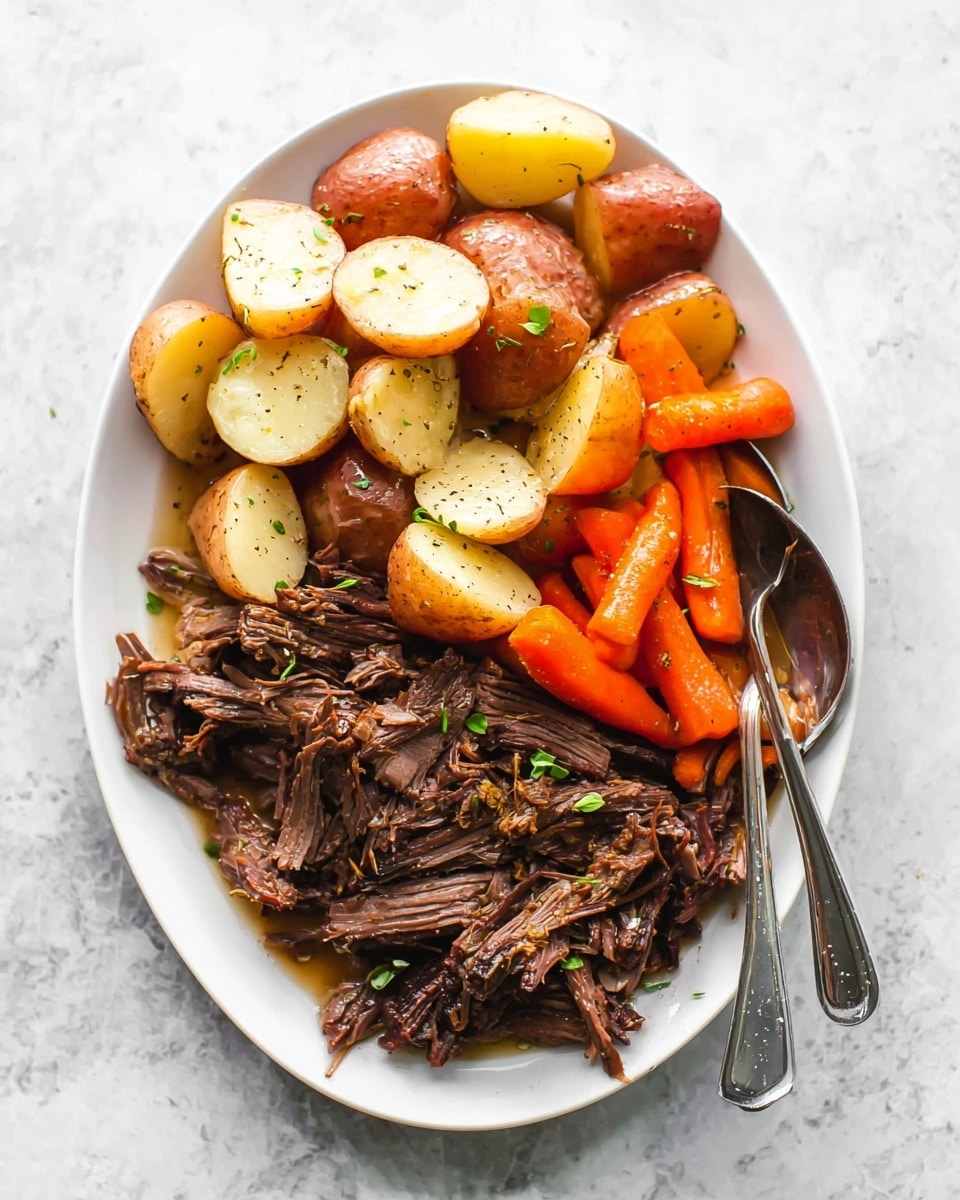 A white oval plate filled with three layers of food: at the bottom, there are dark brown, tender, shredded pieces of pot roast with some small green herb leaves on top; in the middle and upper layers, there are red-skinned potato chunks with soft, pale yellow interiors, some cut in halves and quarters; on the top and mixed in between are bright orange baby carrots. The food is lightly seasoned with black pepper flecks. A silver fork and spoon rest on the right side of the plate, slightly inside the food. The plate sits on a white marbled textured surface. photo taken with an iphone --ar 4:5 --v 7