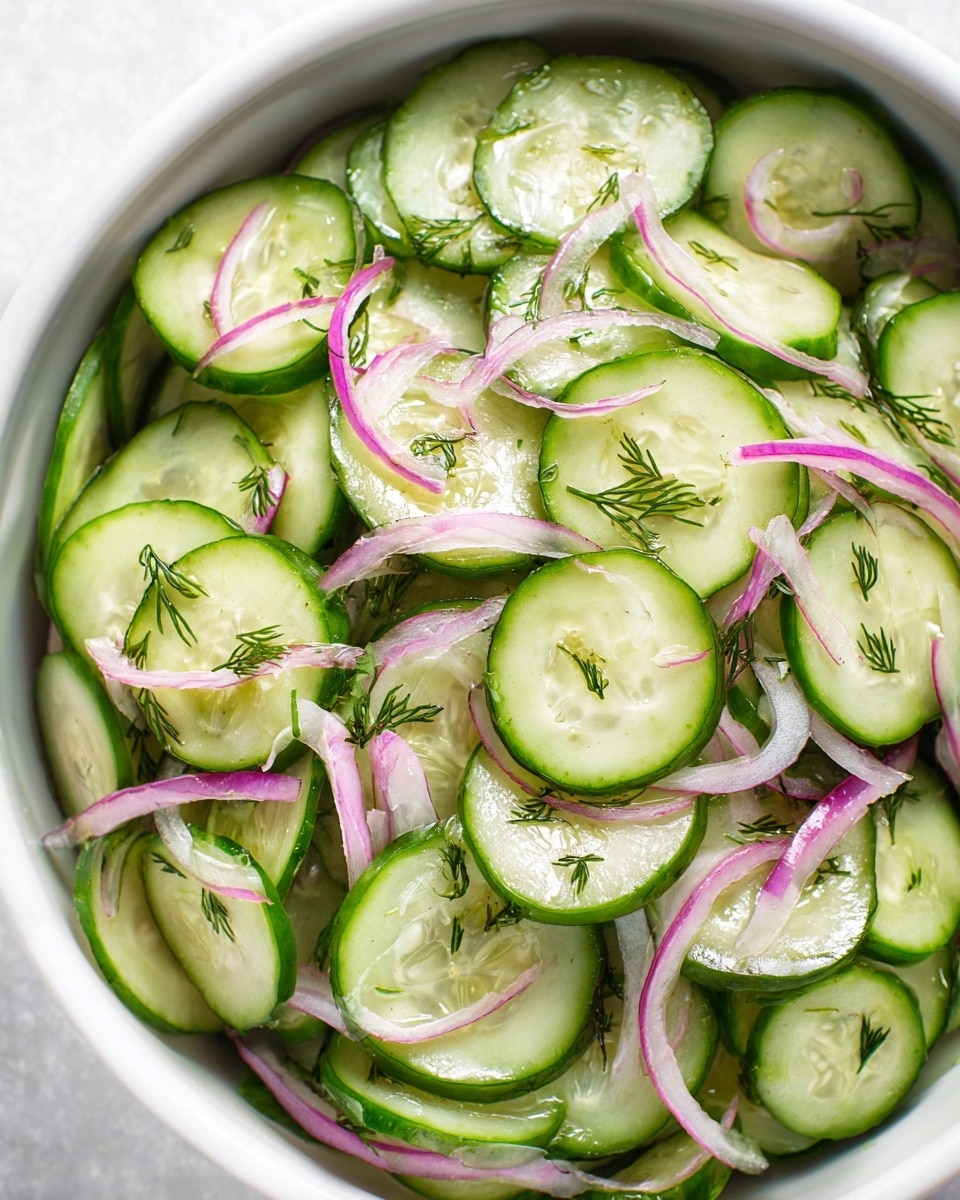 The image shows a fresh cucumber salad with thin, round slices of green cucumbers layered evenly throughout the white bowl. Mixed in are thin strips of light purple red onions adding a contrasting color and texture. Tiny sprigs of delicate green dill are sprinkled on top and between the cucumber layers, giving a fresh herbal touch. The cucumber slices have a shiny, slightly wet texture that suggests a light dressing. The overall look is crisp, simple, and colorful on a white marbled texture background. Photo taken with an iphone --ar 4:5 --v 7