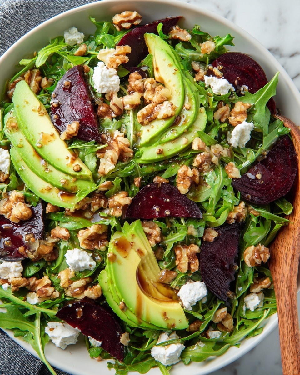 A fresh salad is shown in a white bowl on a white marbled surface. The bottom layer is vivid green arugula leaves, covering the whole bowl. Scattered on top are thick slices of dark purple beets and creamy green avocado wedges with smooth textures. Chopped walnuts are spread unevenly, adding a rough brown and golden layer, and small white dollops of soft goat cheese are sprinkled around. The salad is lightly drizzled with dressing that appears glossy brown in some areas, and a wooden salad spoon is partially visible on the right side. Photo taken with an iphone --ar 4:5 --v 7