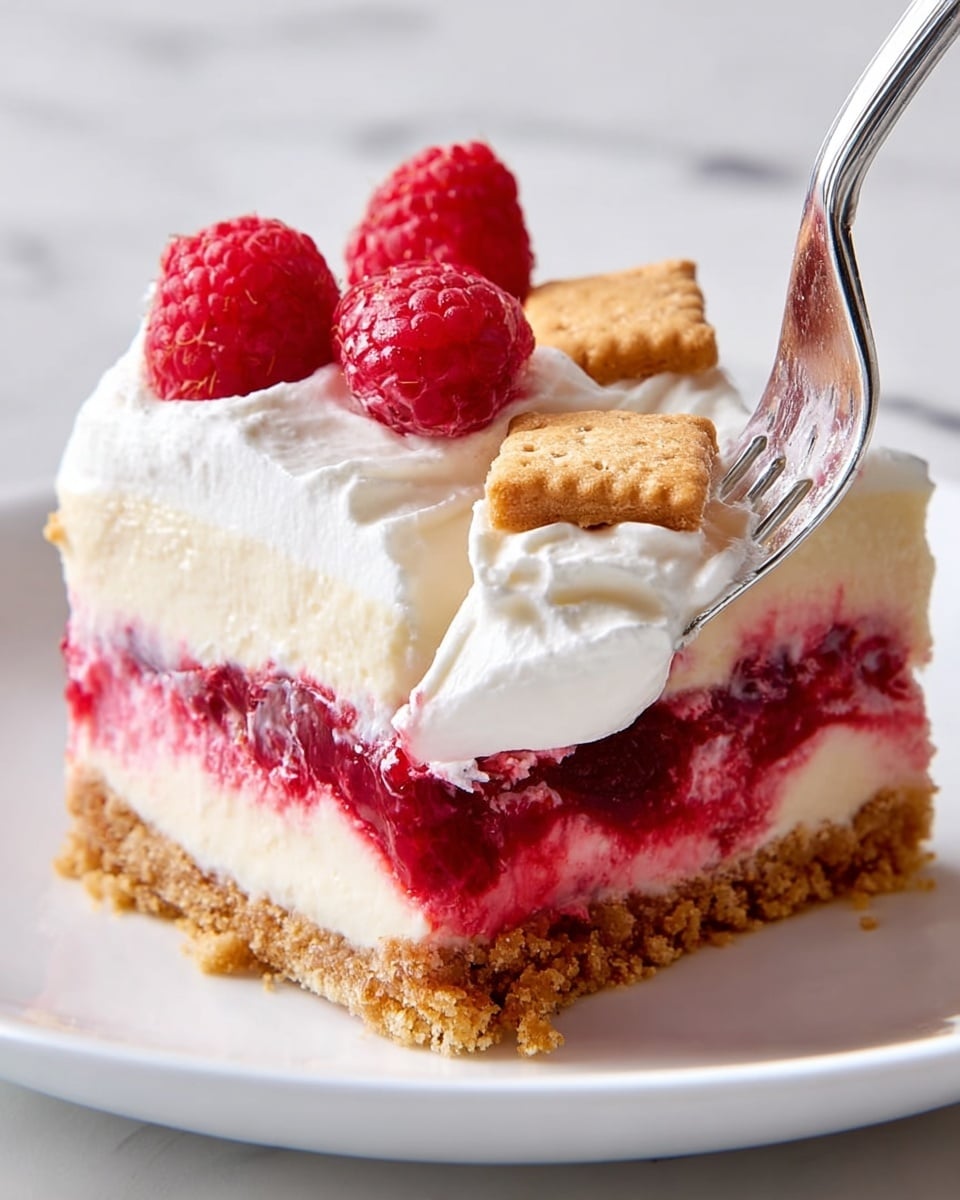 A close-up of a square slice of raspberry cream dessert on a white plate, placed on a white marbled surface. The dessert has four visible layers: a rough crumbly golden brown base, a smooth pale cream-colored layer above it, a thick bright red raspberry jam layer with visible berry pieces, and a fluffy white whipped cream layer on top. Three fresh, bright red raspberries and two broken golden brown cookie pieces sit on the whipped cream. A silver fork is cutting into the dessert, lifting a portion of the whipped cream layer. Photo taken with an iphone --ar 4:5 --v 7