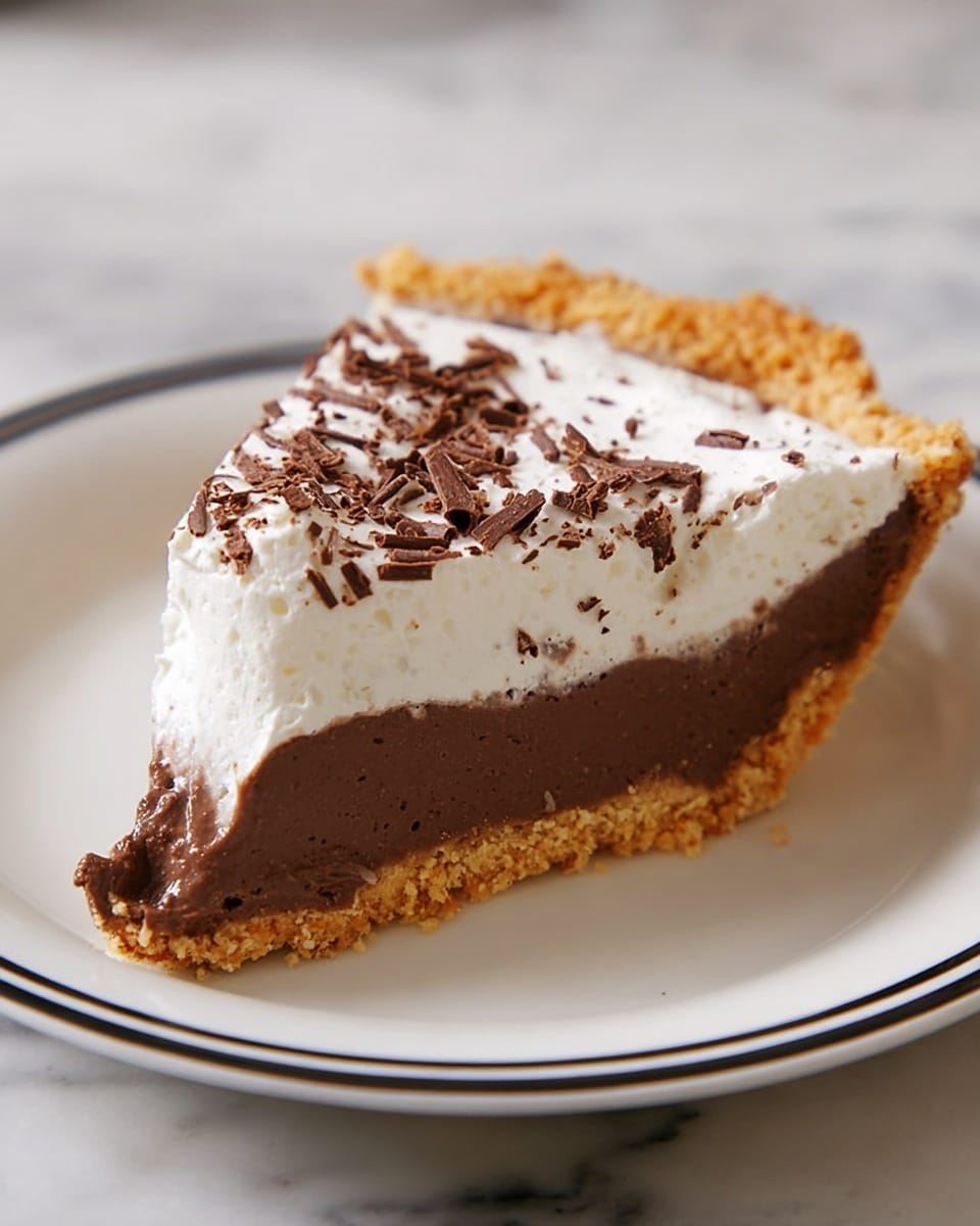 A single slice of pie resting on a white plate with a black trim, placed on a white marbled surface. The pie has three visible layers: the bottom layer is a crumbly, light golden-brown crust with a rough texture; the middle layer is a thick, smooth, dark brown chocolate filling; the top layer is a fluffy, white whipped cream topping sprinkled lightly with small, curled dark chocolate shavings. The edges of the crust are slightly raised above the filling, giving a clear distinction between layers. photo taken with an iphone --ar 4:5 --v 7