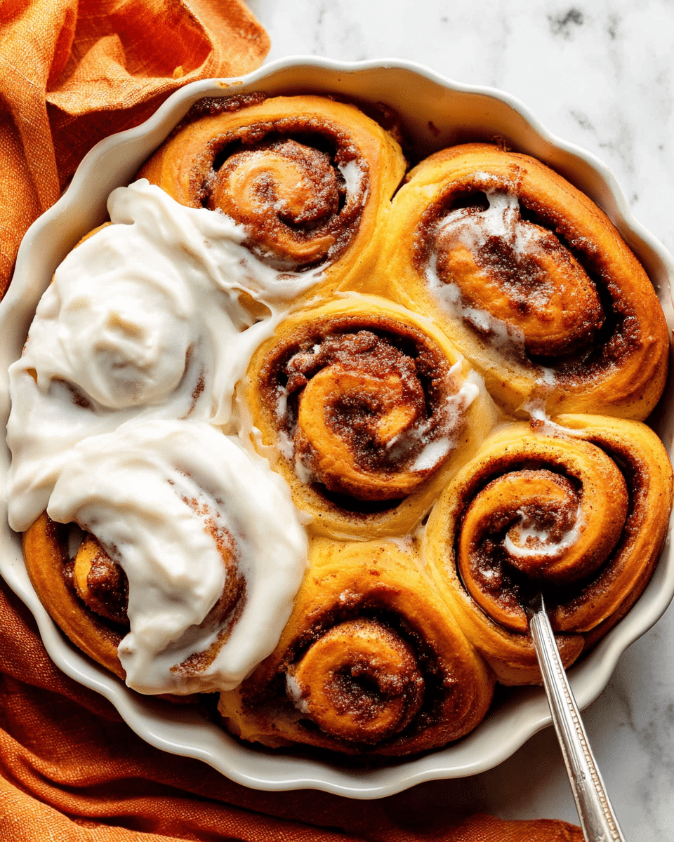 A close-up view of seven golden brown cinnamon rolls arranged closely in a round white scalloped ceramic dish, each roll displaying swirls of dark cinnamon filling with a slightly caramelized texture on top. Four rolls on the left side are generously topped with thick, creamy white icing, dotted with small vanilla specks, partially spread by a silver butter knife held by a woman's hand. The dish rests on a slightly wrinkled orange cloth, placed on a white marbled surface seen faintly at the edges. The warm, soft texture of the rolls contrasts with the smooth, glossy icing, showing layers of dough and cinnamon filling clearly. Photo taken with an iphone --ar 4:5 --v 7