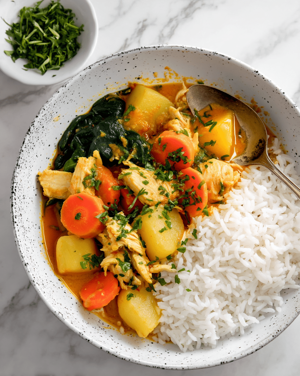 A white speckled bowl is filled halfway with white rice on the left side, while the right side holds a colorful chicken curry with three clear layers: thick orange-yellow sauce at the base, topped with chunks of white chicken pieces, bright orange carrot slices, yellow potatoes, and dark green spinach leaves. The curry is garnished with small green herbs finely chopped and sprinkled on top. A silver spoon resting on the bowl scoops some chicken and spinach. In the background, a small white bowl filled with chopped green herbs is visible on a white marbled surface. photo taken with an iphone --ar 4:5 --v 7