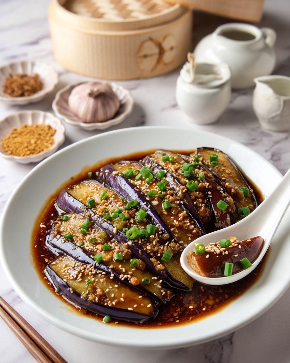 A dish of sliced eggplant with about two layers gently arranged on a white speckled plate, covered with a shiny brown sauce that pools at the bottom, topped with chopped green onions and sprinkled sesame seeds, with a white spoon holding a piece of eggplant resting on the side; the setting includes a white marbled surface with small dishes containing garlic, sesame seeds, and ginger, and a bamboo steamer in the background, photo taken with an iphone --ar 4:5 --v 7