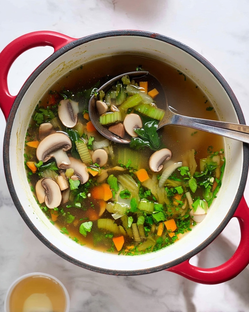 The image shows a large white pot with a red handle filled with a clear vegetable soup. The soup has several layers of ingredients including sliced mushrooms in light cream, chopped green celery stalks, small orange carrot cubes, and green leafy herbs floating on top. A large silver spoon is resting inside the pot, scooping up a mix of these colorful vegetables. The pot is placed on a white marbled surface and a small white cup with a light-colored liquid is visible near the bottom left corner. Photo taken with an iphone --ar 4:5 --v 7
